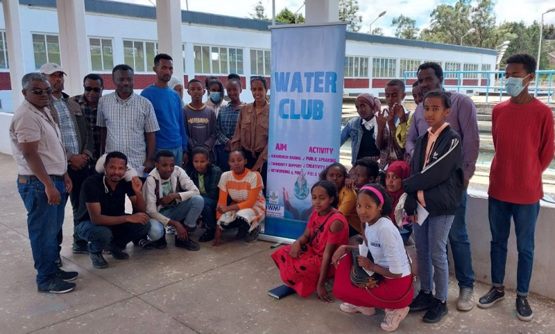 Students and Hub researchers stand together around a pull up banner that reads 'Water Club'